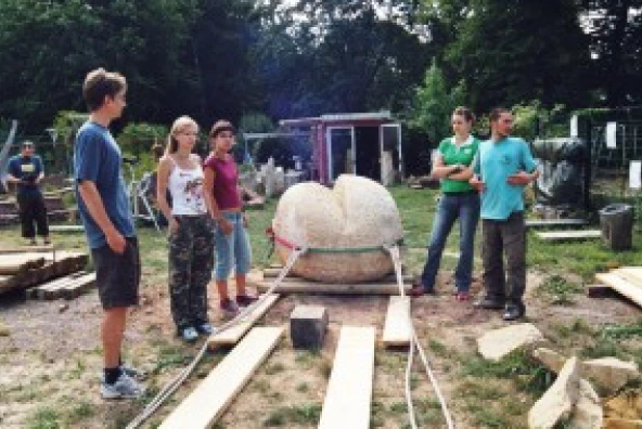 Helfer ziehen eine große Schrippen-Skulptur aus Stein vor die Kapelle